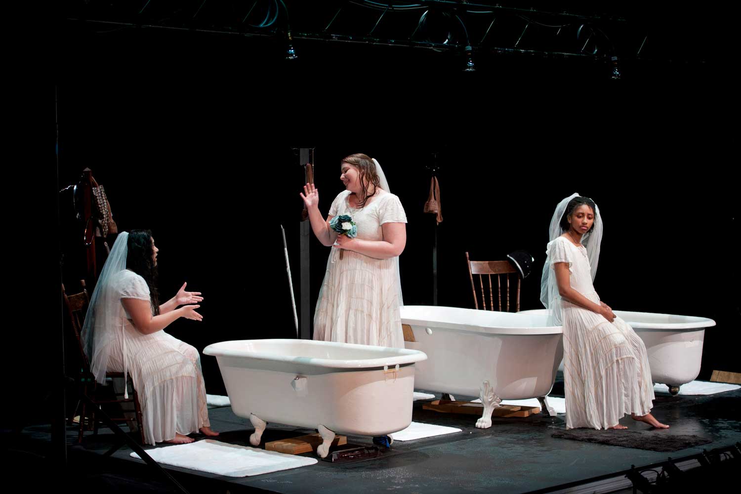 Three girls wearing wedding dresses with bathtubs in background
