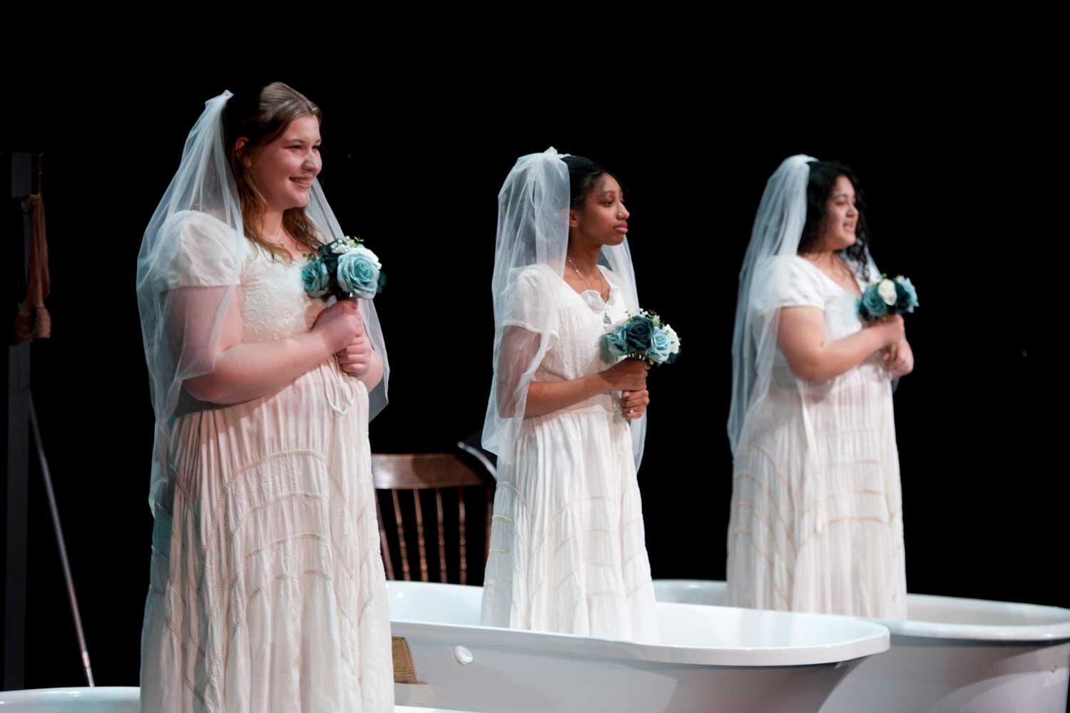Three girls wearing wedding dreses standing in bathtubs