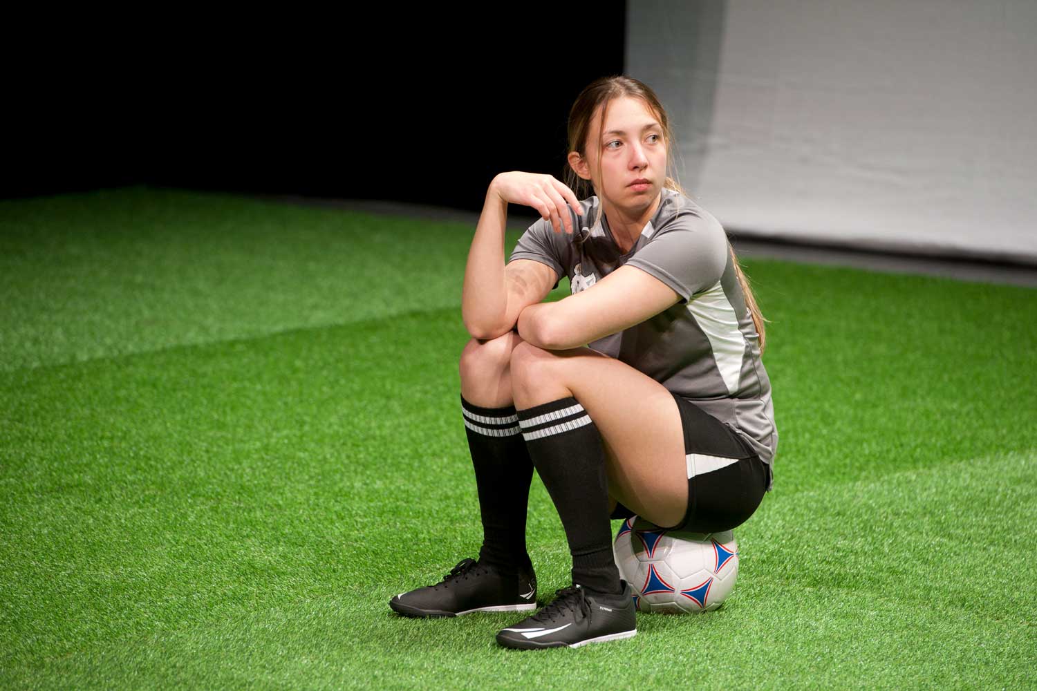 Student in soccer uniform sitting on a ball