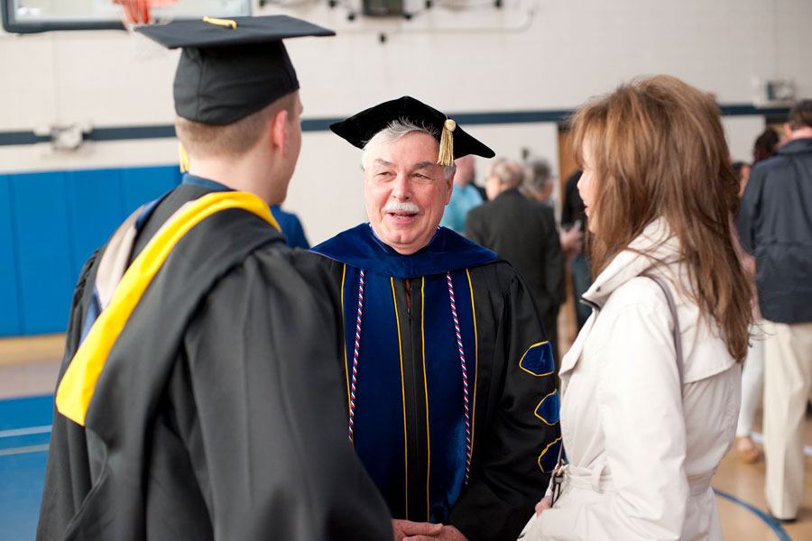 Retired VP Jim Evans speaking to students after a commencement ceremony