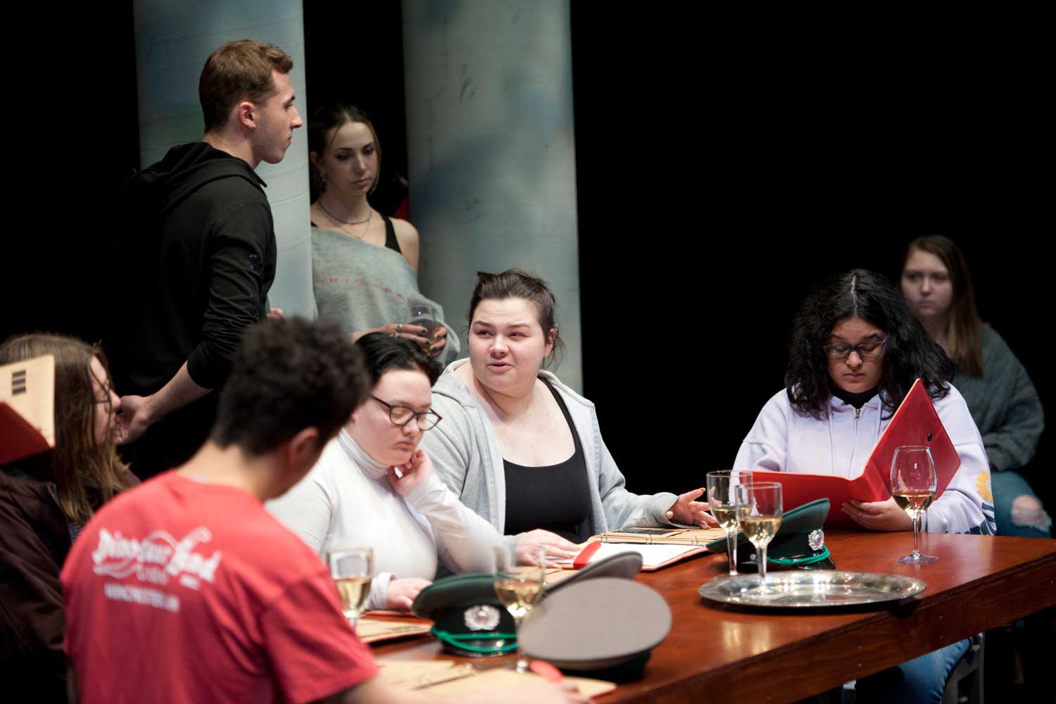 Students sitting at a table acting in a play