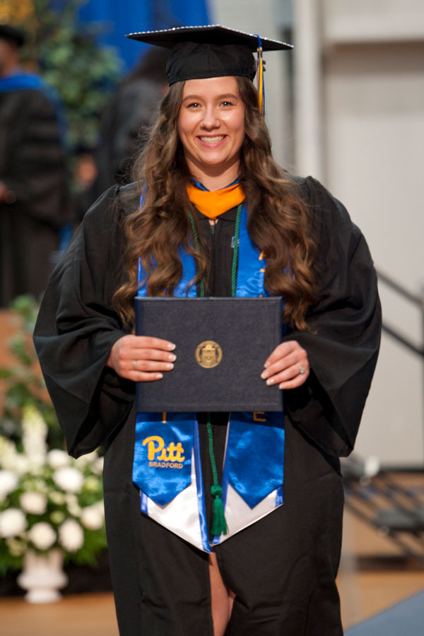 Lexi Peters in regalia holding degree