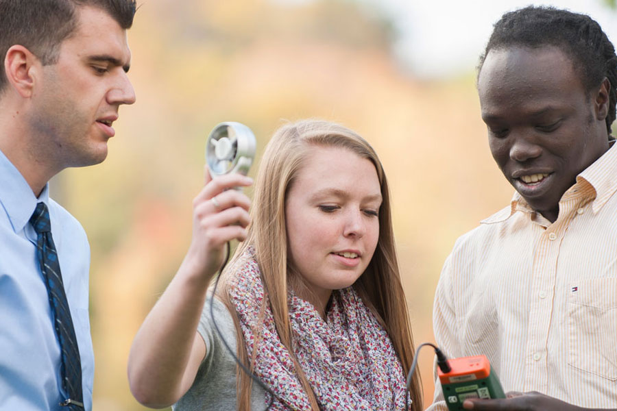 Students and professor using a wind measurement tool