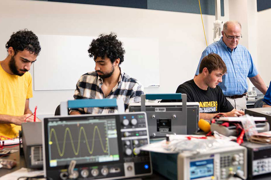 Students with professor in a lab with equipment in the foreground