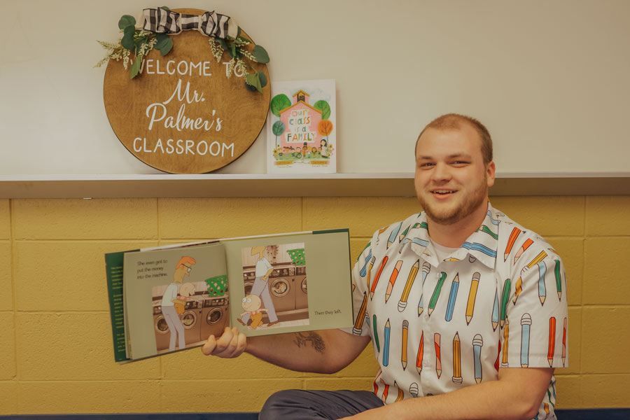 Cole holding up a book in front of stuffed animals