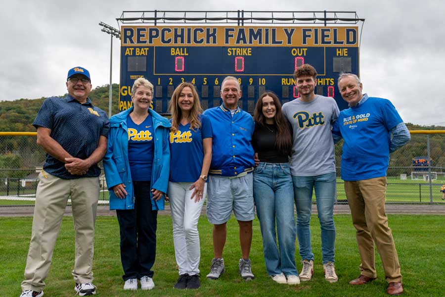 Repchick and family standing in front of their dedication sign that says "Repchick Family Field"