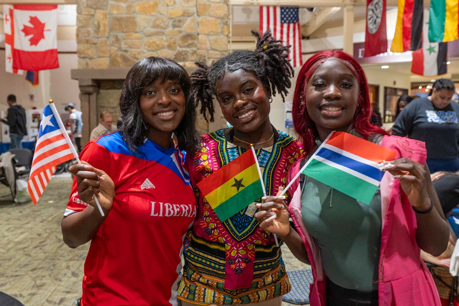 Three students holding flags of different countries