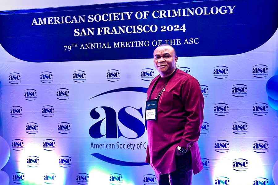 Dr. Obinna Ezeihuoma in front of a backdrop for American Society of Criminology