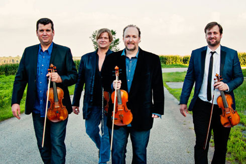 Members of the DePue Brothers band walking on a road with fiddles