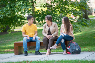 Catherine Koverola sitting on bench with students