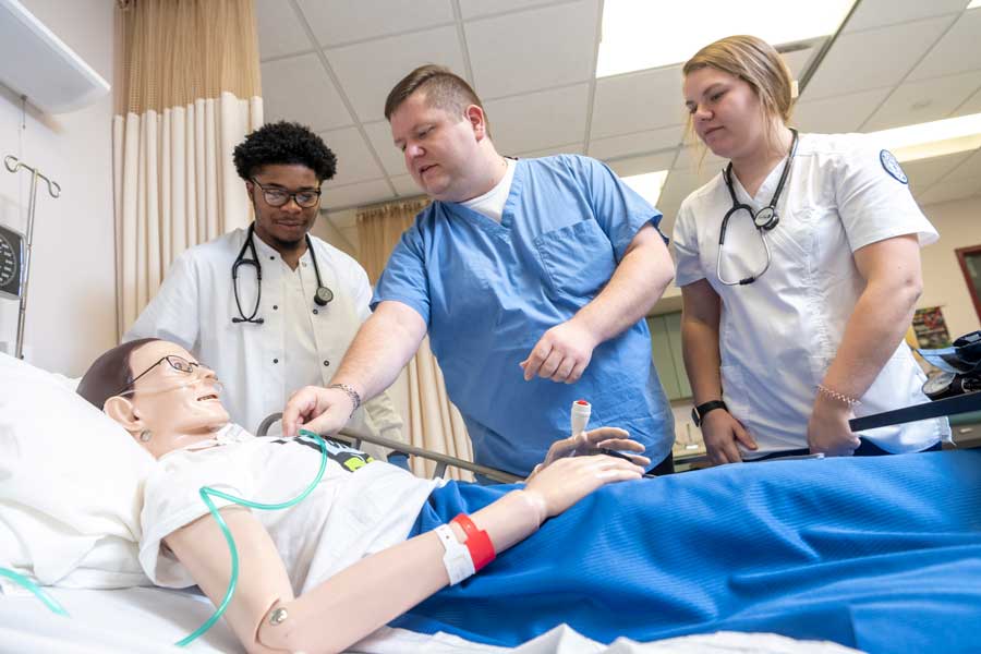 Photo of students with a professor practicing nursing exercises on a dummy