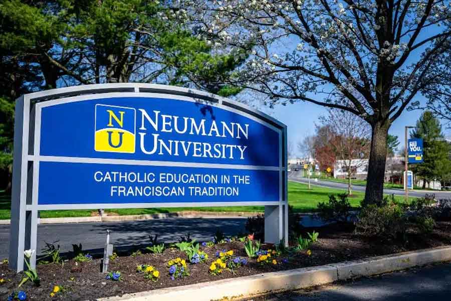 A sign for Neumann University in front of some trees