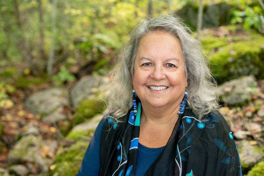 Robin Kimmerer in front of a nature scene, smiling