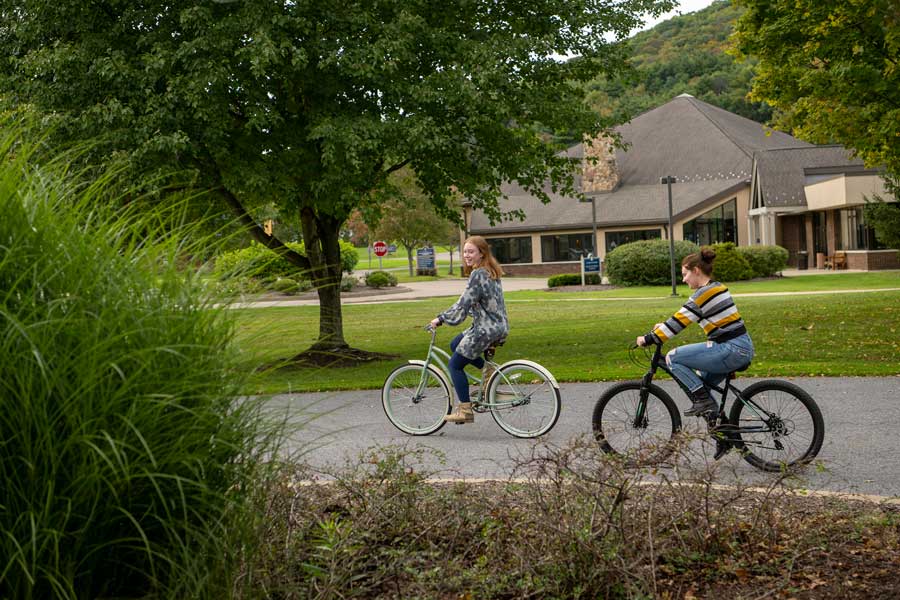 Two students riding their bikes on campus