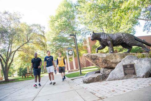 Students walking by panther statue