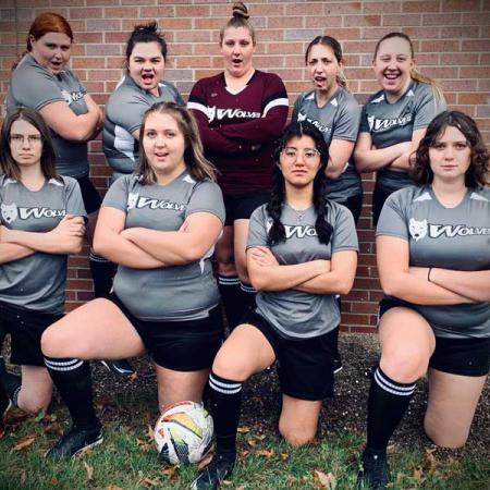 9 female actors in grey soccer uniforms for their production "The Wolves"