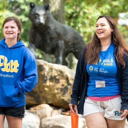 Two students walking in front of the panther statue in the quad